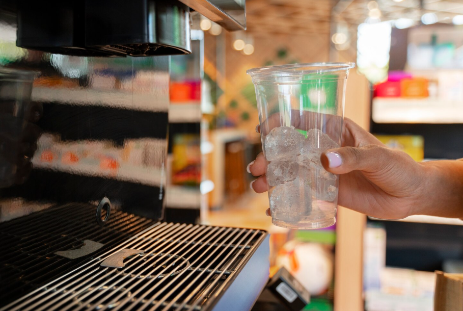 Hand holding a cup of ice at a café drink machine